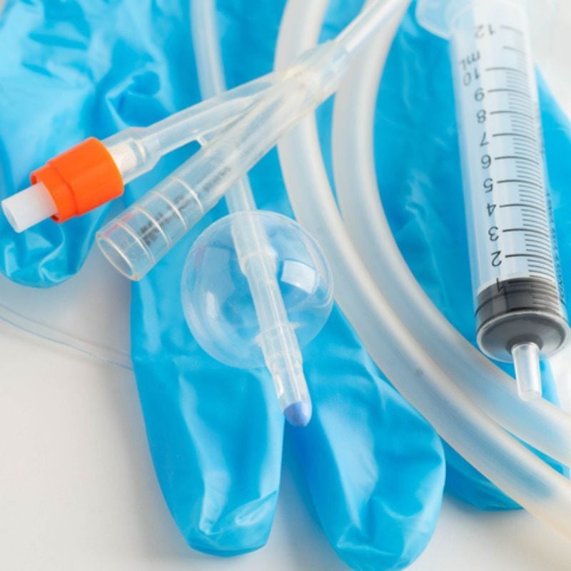 Opened foley catheter sitting atop a blue latex glove.