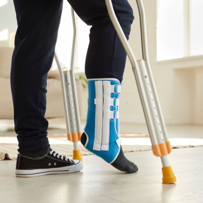 Close up of crutches and foot in brace.