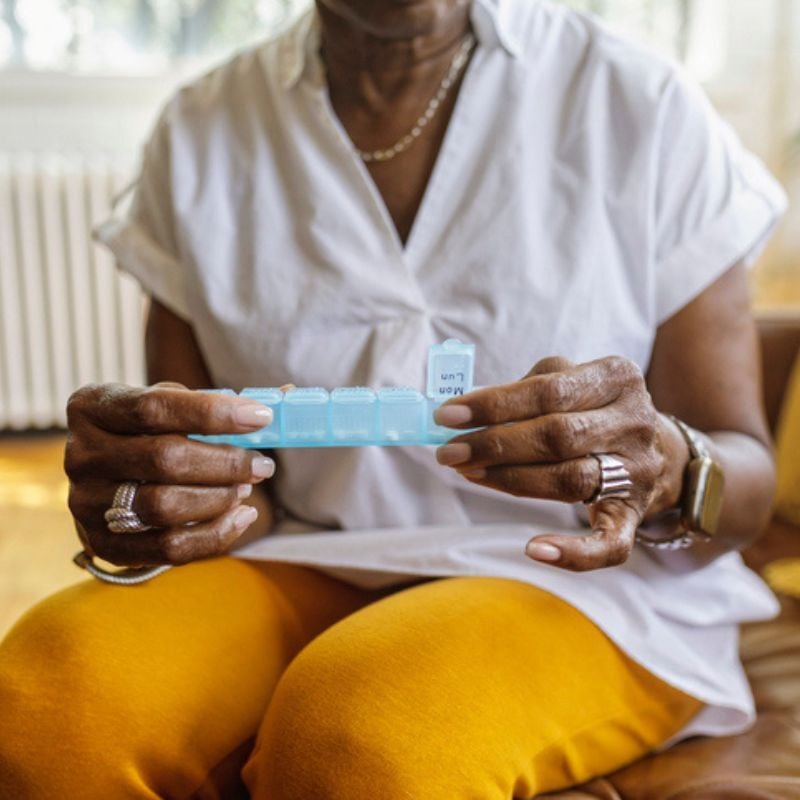 Woman holds pill tabber with tab open.