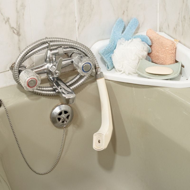 Shower hose hands off facuet in tab next to soap dish.