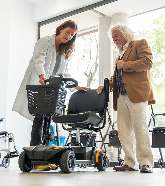 A caregiver assists a patient in an electric wheelchair in a healthcare setting