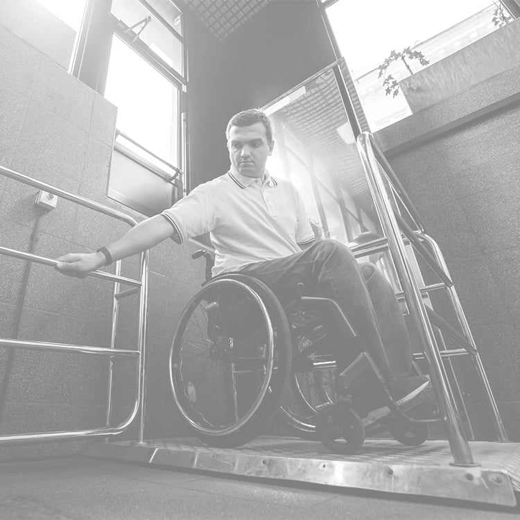 Man in wheelchair leans forward to grab support bar for balance in hallway