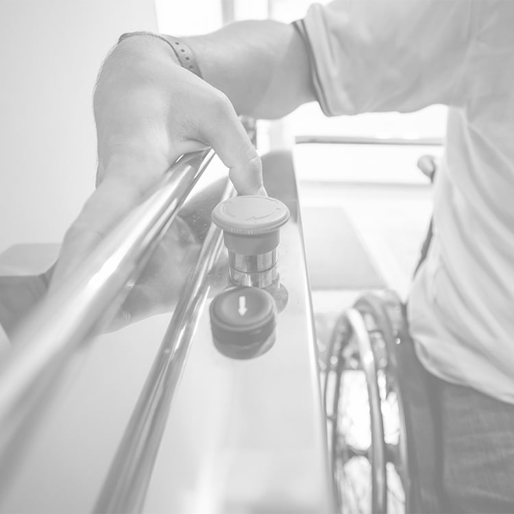 Close-up of man’s hand gripping grab bar for support, partial view of wheelchair visible