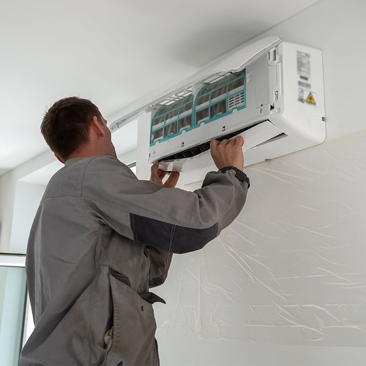 Man installing wall mounted air conditioning unit in home